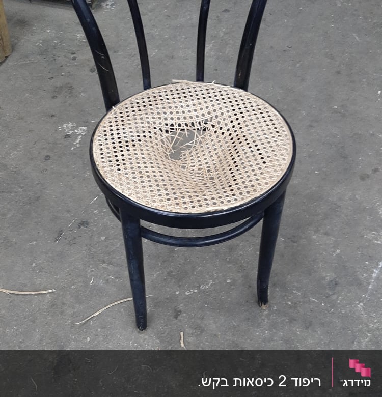 כיסא עם מושב קש קרוע על רצפת בטון